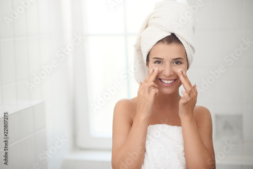 Junge hübsche Frau trägt Gesichtscreme auf