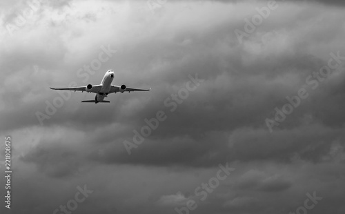 Commercial airplane on grey sky and clouds with copy space. Failed vacation. Hopeless and despair concept. Moody sky and transport plane. Sad emotional scene. Background of aircraft flight.