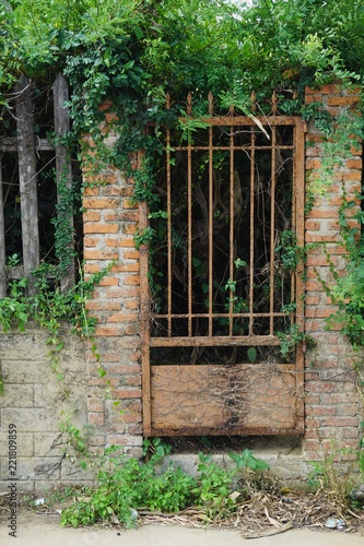 Rusty iron gate set in an ancient brick and stone wall in Southeast Asia © John
