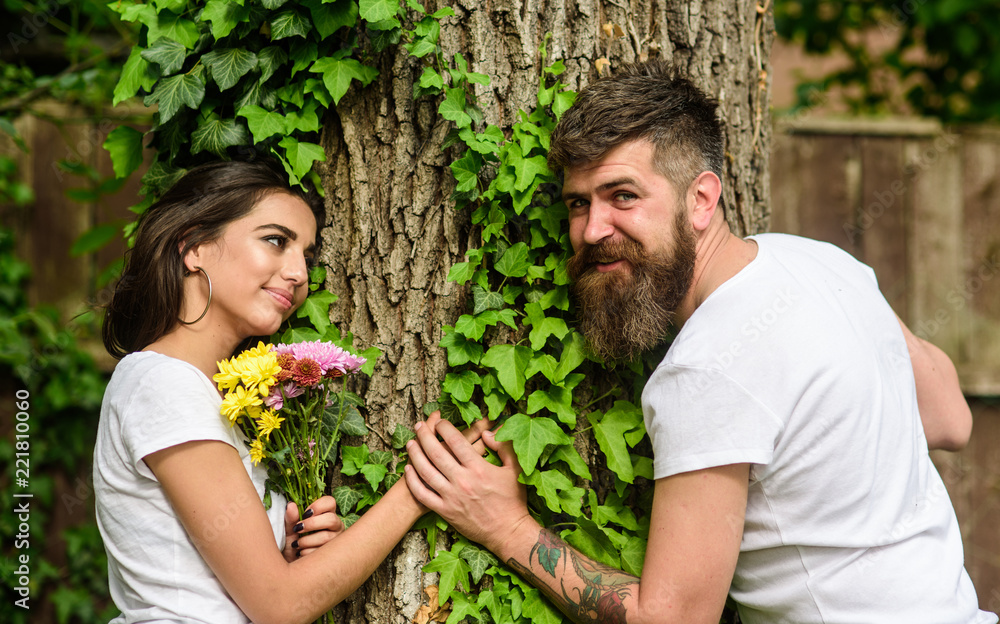 Pleasant date in nature environment. Couple in love romantic date walk nature tree background. Couple in love lean on trunk with ivy. United with nature. Man bearded hipster holds hand girlfriend