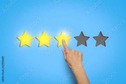 Female hand leaves a rating of three stars out of five possible
