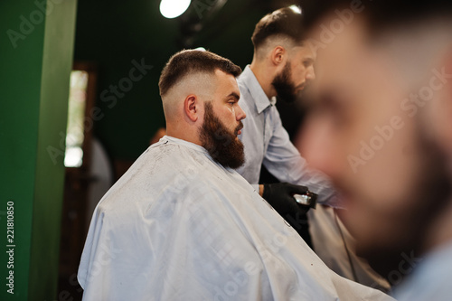 Handsome bearded man at the barbershop, barber at work.