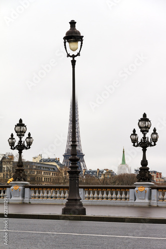 Funny view on the Eiffel tower in the mist in Paris in winter with a lantern in front 