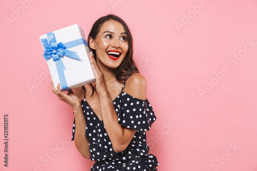 Woman isolated over pink background holding susprise gift box. photo