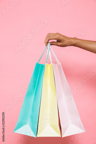 Woman isolated over pink background holding shopping bags