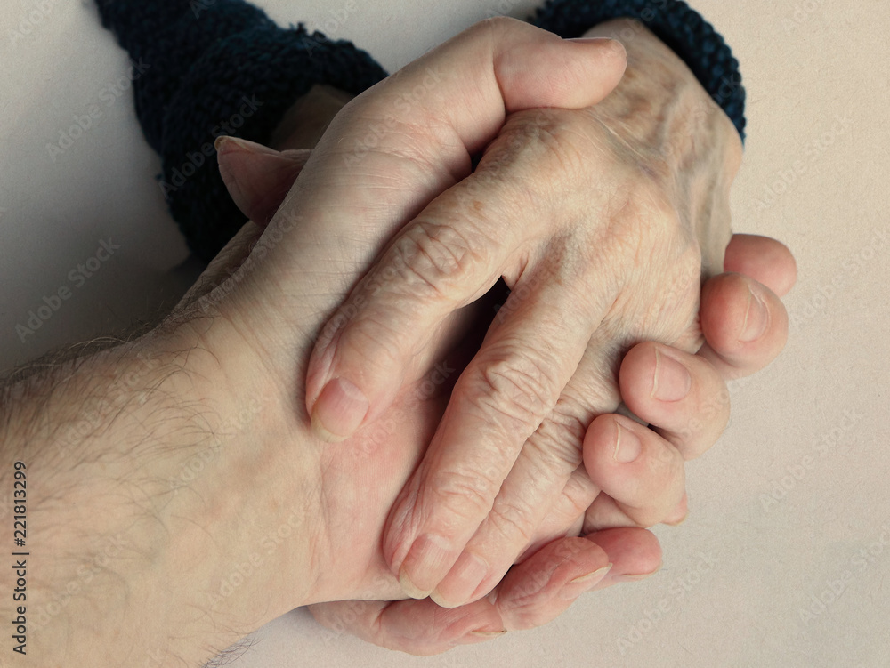 Fototapeta premium Hands of old woman. With a hand of a man (son, grandson, doctor, helper)