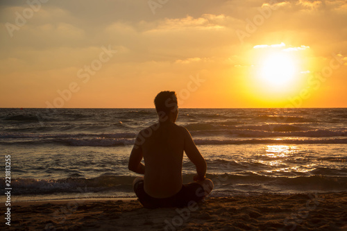 On a sunset background silhouette of a guy on the beach of the beautiful sea © Iryna