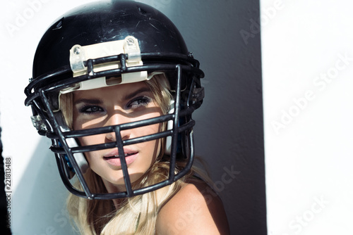 close-up portrait of young woman in sport bra and american football helmet on white © LIGHTFIELD STUDIOS
