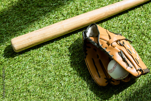 Photography top view of baseball glove with ball and bat lying on green grass