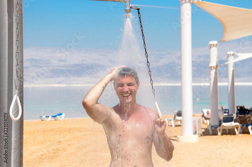 A young attractive man is standing in the shower with a spray around