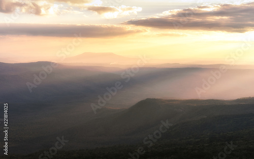 Fog in mountains, fantasy and colorful nature landscape and ray of sunlight through clouds, view from the top view of mountains. 
