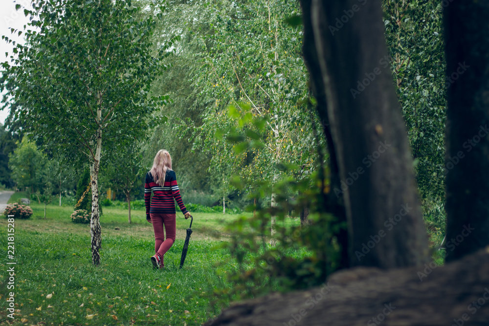 Girl in pullover with black umbrella walk in county side village outdoor natural landscape environment autumn season time with creative concept shot between trees Girl in pullover with black umbrella walk in county side village outdoor natural landscape environment autumn season time with creative concept shot between trees