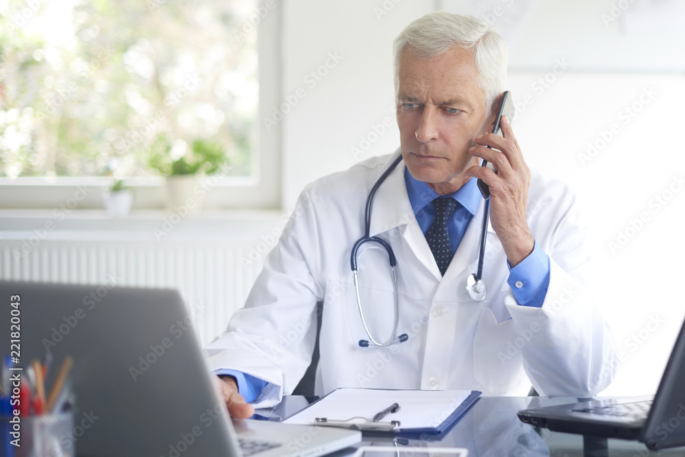 Male doctor making call. Shot of a doctor sitting at consulting room and talking with his patient on phone. Male doctor making call. Shot of a doctor sitting at consulting room and talking with his patient on phone.