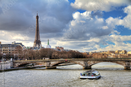 Tourist boat at the Seine in Paris with the Eiffel tower in the background on a cloudy winter day