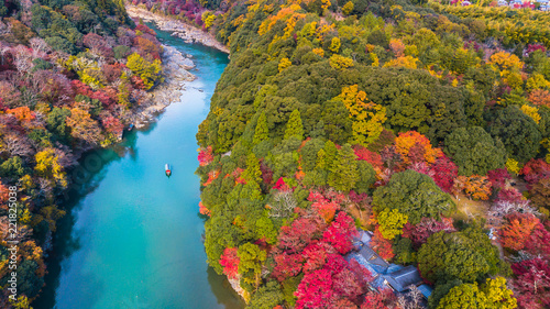 Aerial view boat on the river bring tourist people to enjoy autumn colors along katsura river to Arashiyama mountain area during fall season in Arashiyama, Kyoto, Japan. photo
