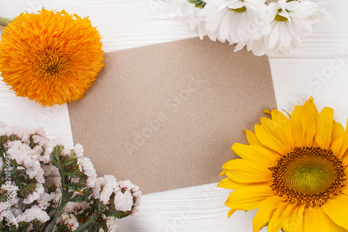 Fototapeta Naklejka Na Ścianę i Meble -  Old beige paper and variety of flowers. Space for your text. White wood background.