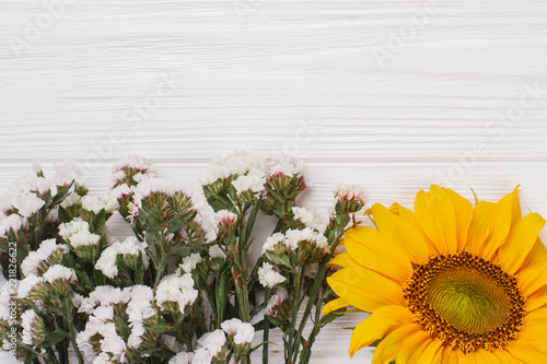 Fototapeta Naklejka Na Ścianę i Meble -  Sunflower and statice limonium flowers. White wood background and free space for text, copyspace.