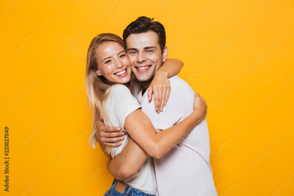 Loving couple standing isolated over yellow wall background hugging. Loving couple standing isolated over yellow wall background hugging.