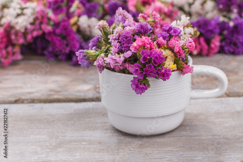 Wallpaper Mural Multicolored statice flowers in white tea cup. Wooden desk background. Torontodigital.ca