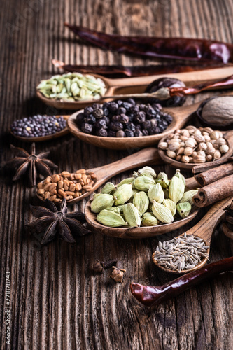Different types of whole Indian spices in wooden background close-up.  Black pepper, fenugreek, anise, cinnamon, cardamom, nutmeg, clove, cumin. Healthy food.