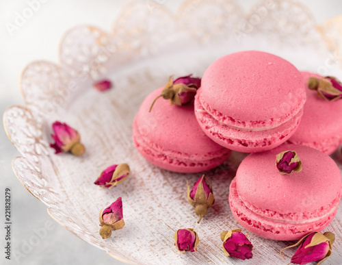 Pink macaroons on a vintage plate and dried flower buds. Pastel colored.