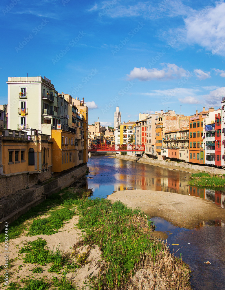 Scenic landscape of picturesque multocolor houses overlooking the river Onyar with red metal brige in Girona  Spain 
