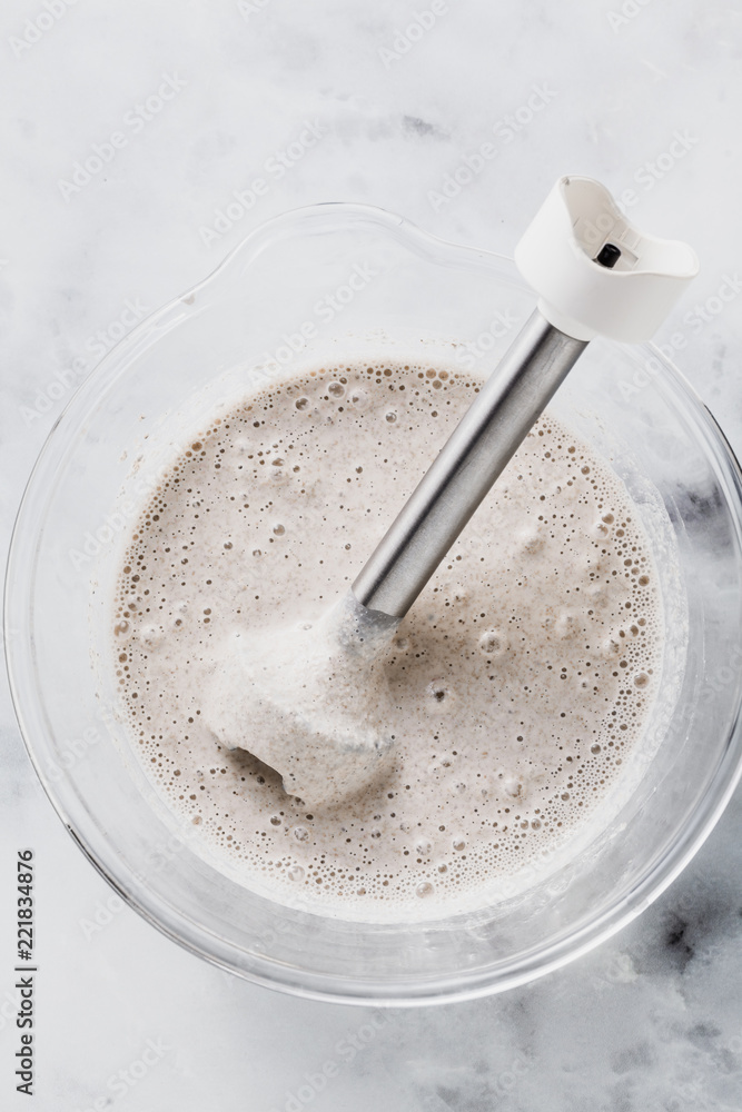prepare batter for pancakes in a glass bowl with a hand blender on a marble table prepare batter for pancakes in a glass bowl with a hand blender on a marble table