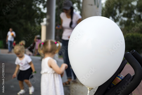 White balloon close-up and children playing in the background.