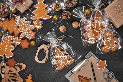 Billede på lærred A Christmas gingerbread cookie in the shape of a Christmas tree in a cellophane packing on the background of a dark table