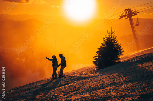 Silhouette of two skiers in winter nature. Ski resort, sunset light