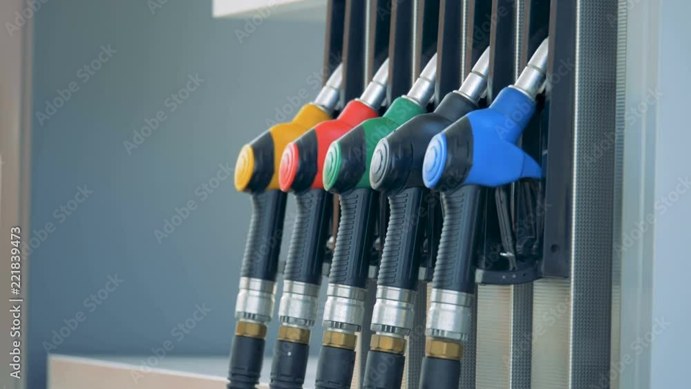 One of the gas pistols is being put back into the pump by a male hand. Gasoline fuel, gas station concept. One of the gas pistols is being put back into the pump by a male hand. Gasoline fuel, gas station concept.