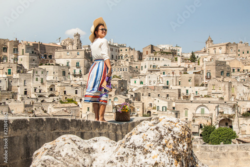 Fényképezés Young elegant woman tourist in historical Matera town in Italy standing on a wal