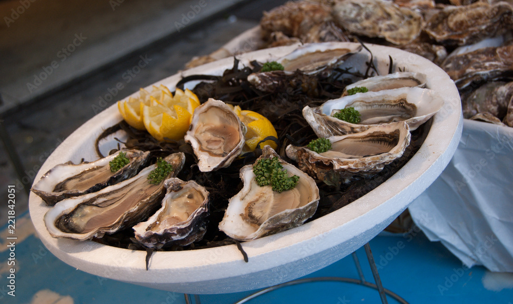 Fresh oysters with lemon on plate. Fish market in France.