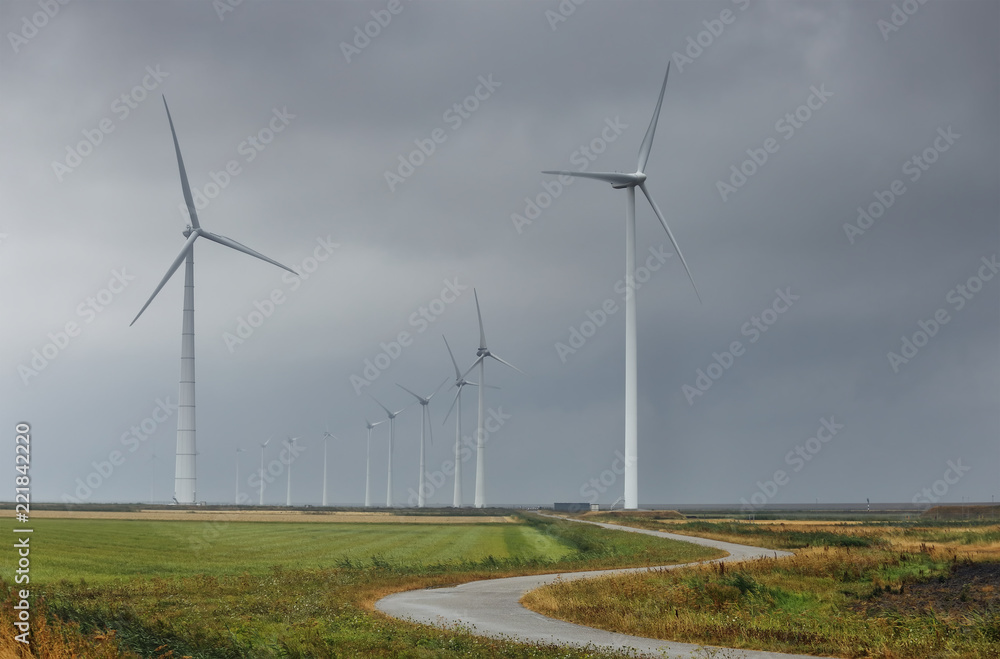 road between wind turbines on cloudy day road between wind turbines on cloudy day