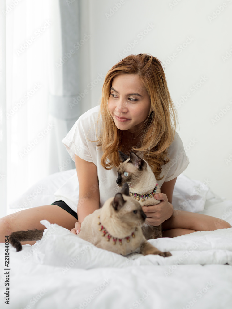 Happy Asian woman and her cats on bed. Happy Asian woman and her cats on bed.