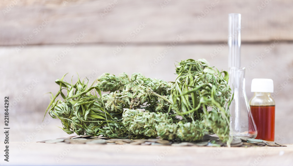 Green leaves of medicinal cannabis with extract oil on a wooden table