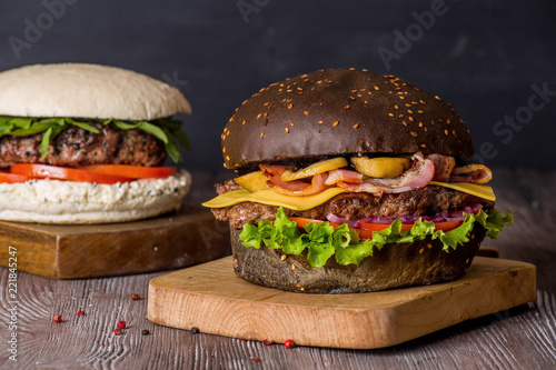 Hamburger with beef and bacon and a white hamburger with french fries on a wooden background.
