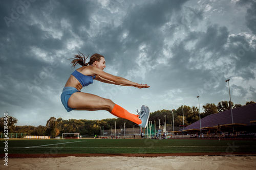 Female athlete performing a long jump during a competition at stadium. The jump, athlete, action, motion, sport, success, championship concept