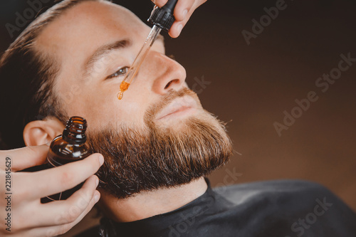 Oil for beard in dropper, process of moisturizing hair.