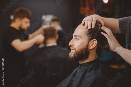 Barber shop. Man in barbershop chair, hairdresser styling his hair