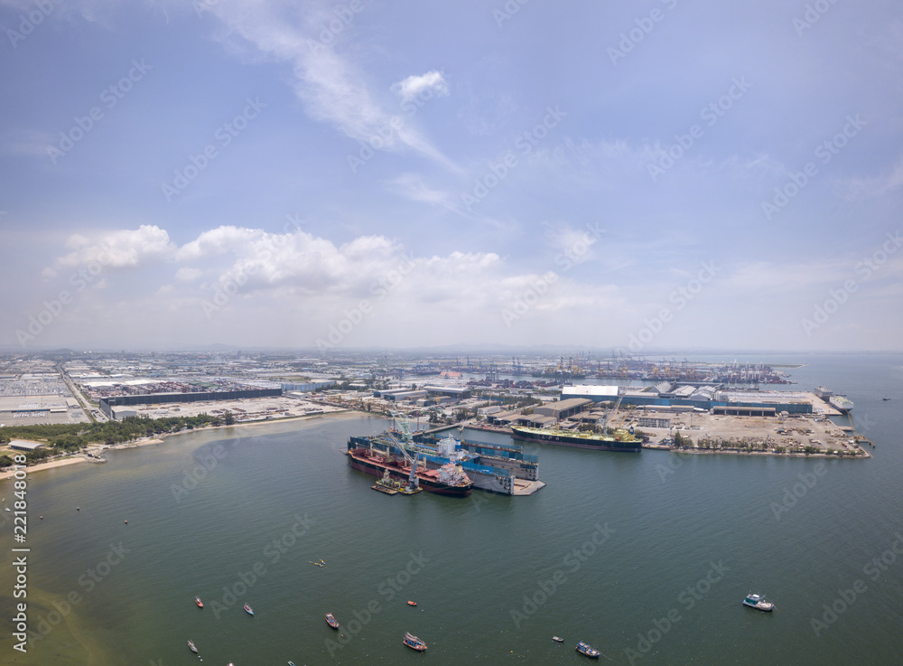 Aerial view of logistics concept floating dry dock servicing cargo ship and commercial vehicles, cars and pickup trucks waiting to be load on to a roll-on/roll-off car carrier ship at Laem Chabang 