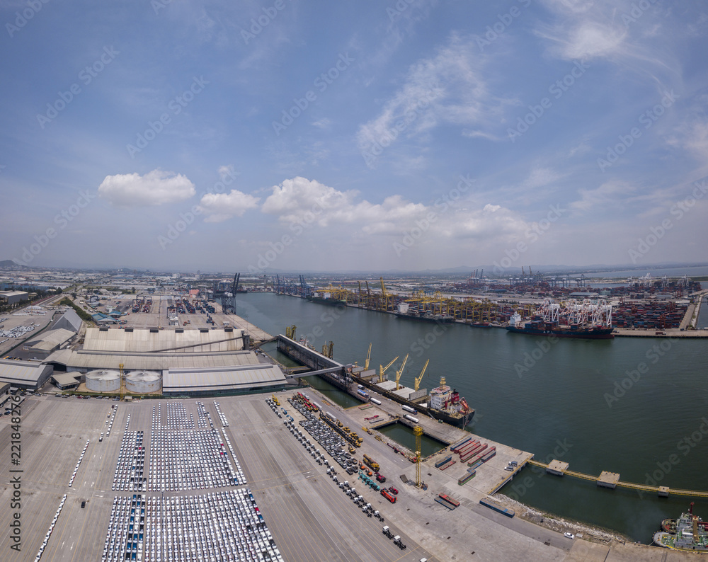 Obraz premium Aerial view of logistics concept floating dry dock servicing cargo ship and commercial vehicles, cars and pickup trucks waiting to be load on to a roll-on/roll-off car carrier ship at Laem Chabang 