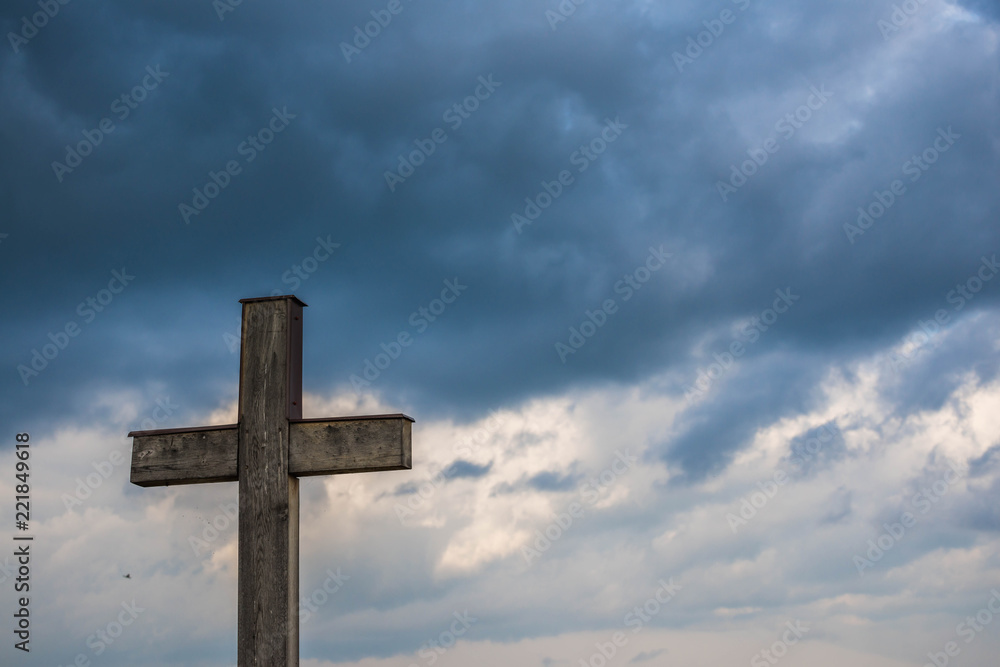 Simple oak catholic cross, storm clouds in the background, space for text.