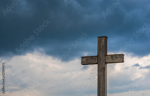 Simple oak catholic cross, storm clouds in the background, space for text.