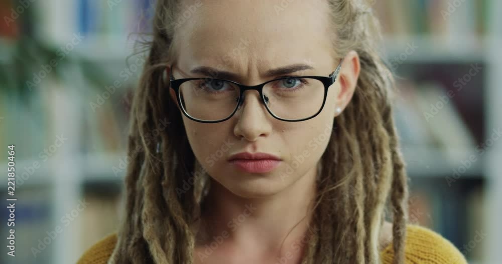 Close up of the young woman in the glasses and with dreadlocks being offended, sad and angry looking to the camera and shaking her hands like saying no. Close up of the young woman in the glasses and with dreadlocks being offended, sad and angry looking to the camera and shaking her hands like saying no.