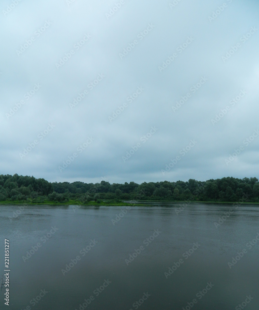 water, sky (cowered with clouds) and far away forest - calm background