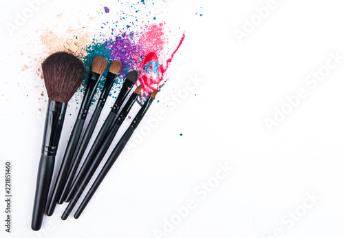 Makeup brushes on white background with colorful powder. Make-up background.