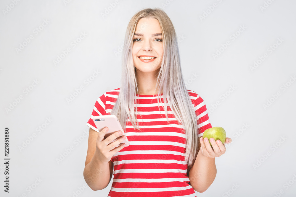 Portrait of a beautiful young woman holding an apple and phone on a white background. Portrait of a beautiful young woman holding an apple and phone on a white background.