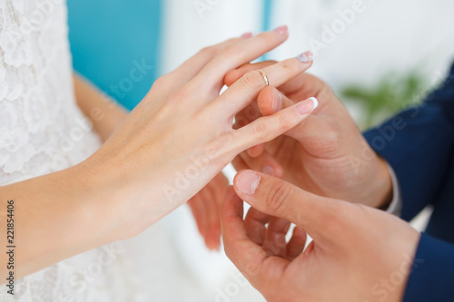 The groom carefully puts the ring on the finger of the future wife