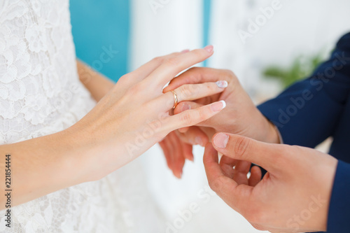 The groom carefully puts the ring on the finger of the future wife